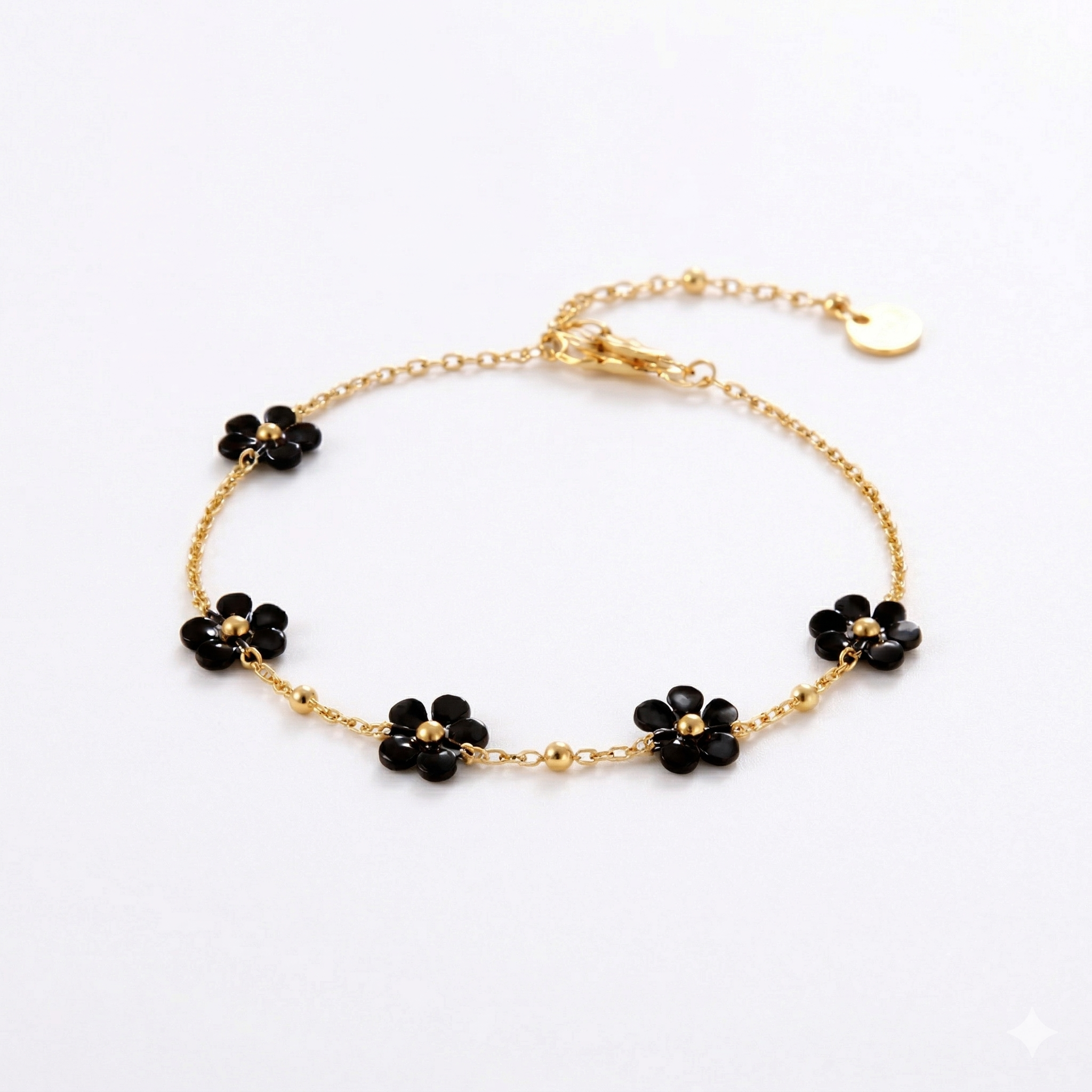 Gold bracelet with black flower-shaped charms on a white background